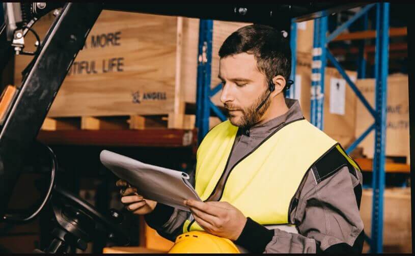 a man riding a forklift truck, communicating instructions while working at the site, through his aftershokz opencomm bone conduction headset boom mic