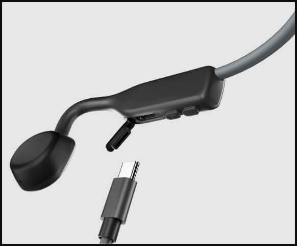 Close-up of black bone conduction headphones with USB-C charging cable, headphones with charging port and USB-C cable