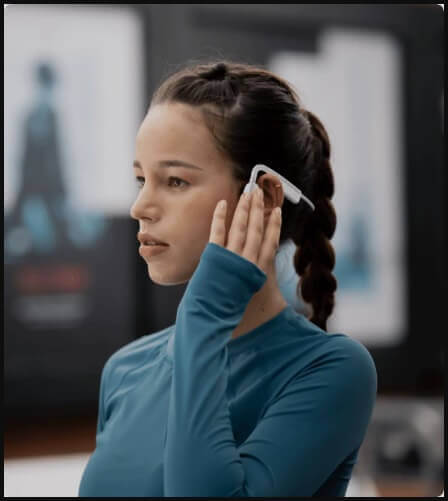 Person using bone conduction headphones to make a phone call in a busy city, white bone conduction headphones with built-in microphone for phone calls