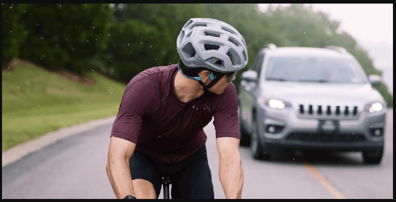 man wearing shokz openrun pro while cycling outdoors on the road with a sport suv in the background