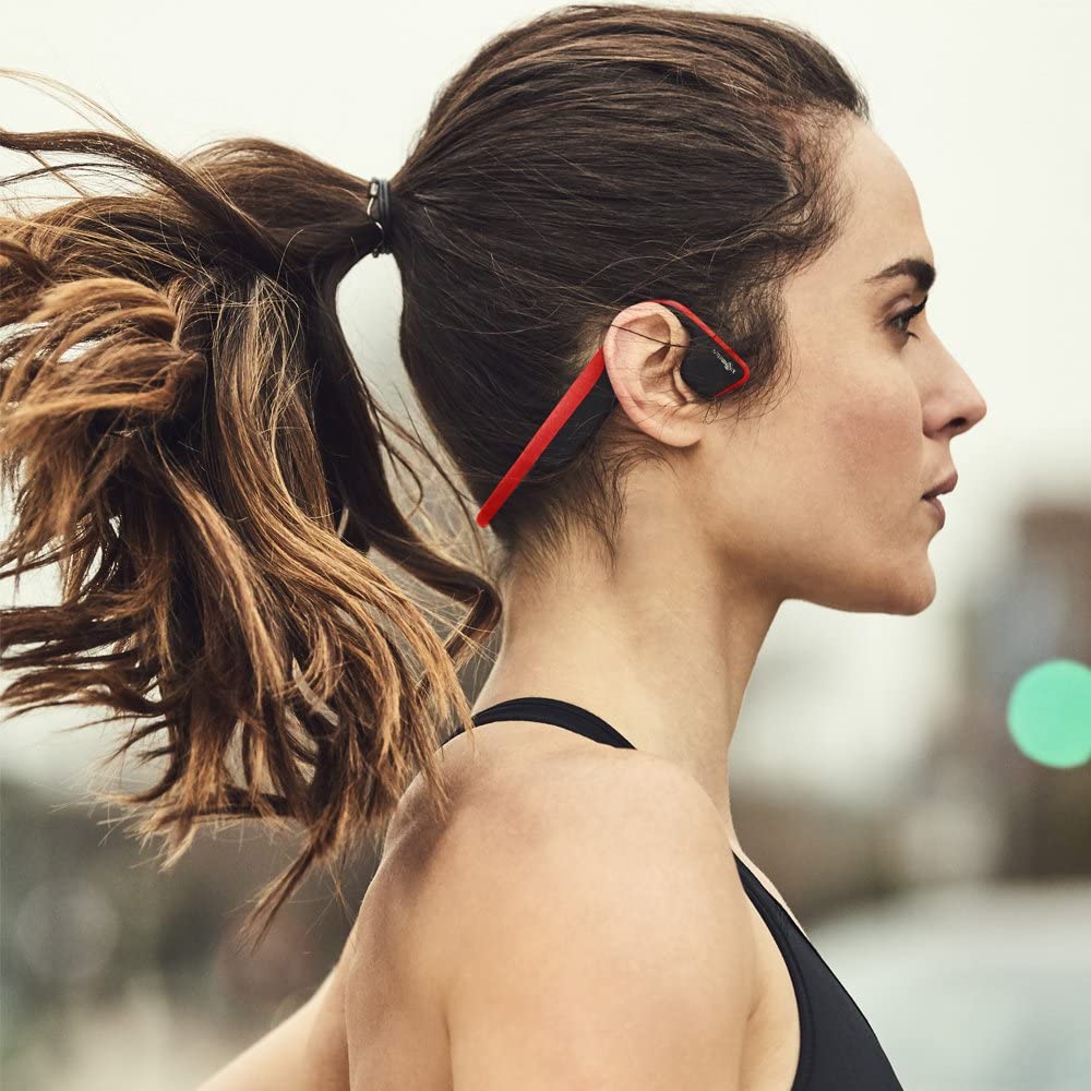 a lady on the jogging trail outdoors wearing the aftershokz titanium red headphone