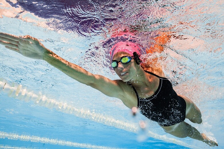 Person swimming with swimming bone conduction headphones.