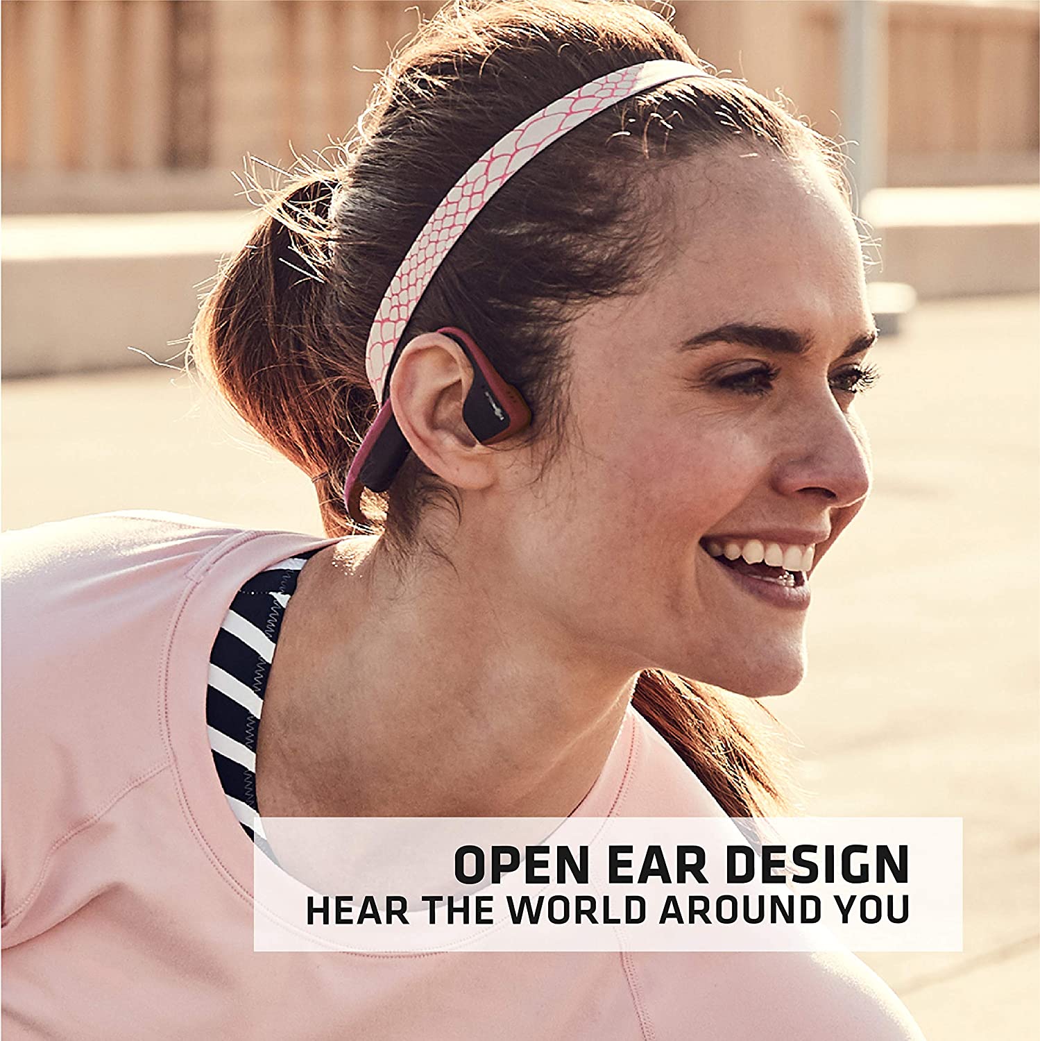 a woman on the open playground listen to music through the open-ear aftershokz trek titanium