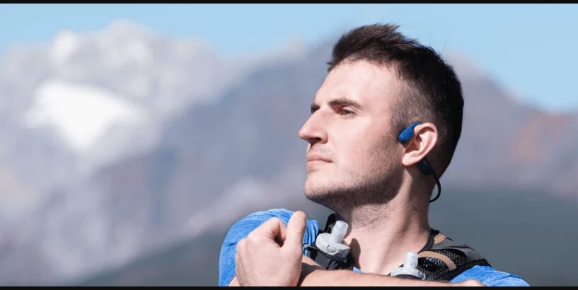 man listening to music through the openrun mini as he exercises close to the mountains