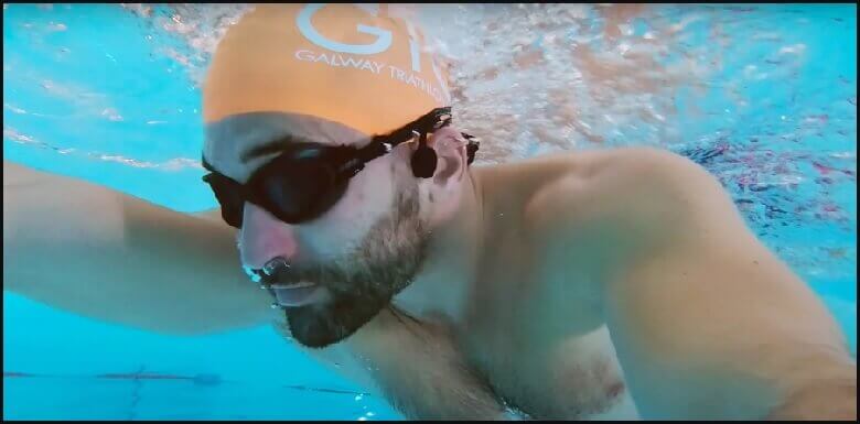 Swimmer wearing waterproof bone conduction headphones for underwater music experience.