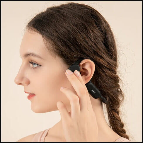 Person wearing wireless bone conduction headphones connected to a smartphone via Bluetooth.