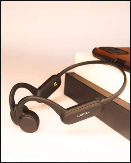 Bone conduction headphones alongside a smartphone with cameras and photography equipment for spring expeditions.